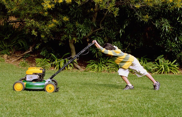 Boy (8-10) mowing lawn