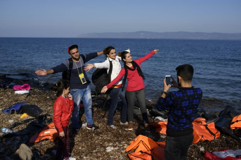 Migrants pose for photographs on a beach as they arrive by boat on the Greek island of Lesbos after crossing the Aegean sea from Turkey on October 9, 2015