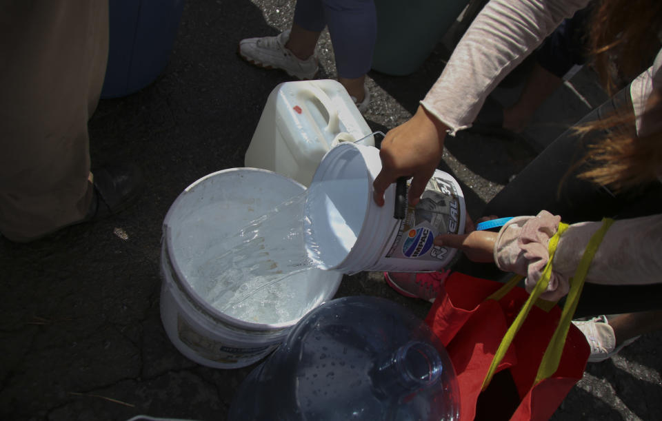 Neighbors collect water in plastic containers at a public collection point in Monterrey, Mexico, Monday, June 20, 2022. Local authorities began restricting water supplies in March, as a combination of an intense drought, poor planning and high use has left the three dams that help supply the city dried up, with thousands of homes not receiving any water for weeks. (AP Photo)