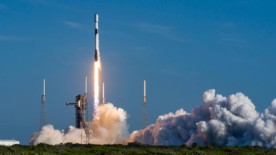     Eine schwarz-weiße SpaceX Falcon 9-Rakete startet in einen blauen Himmel. 