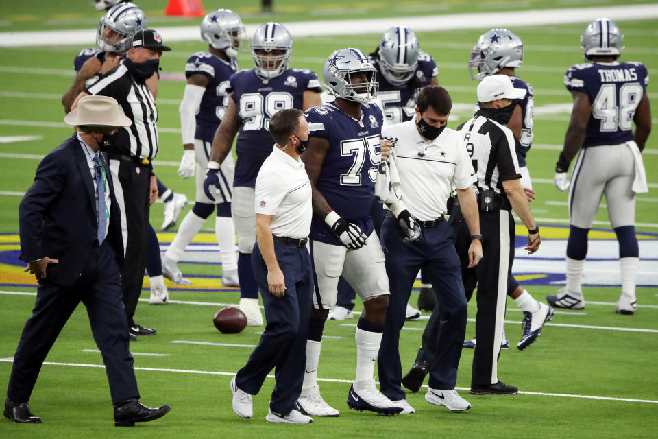 Cameron Erving walks off the field with help from Cowboys trainers.