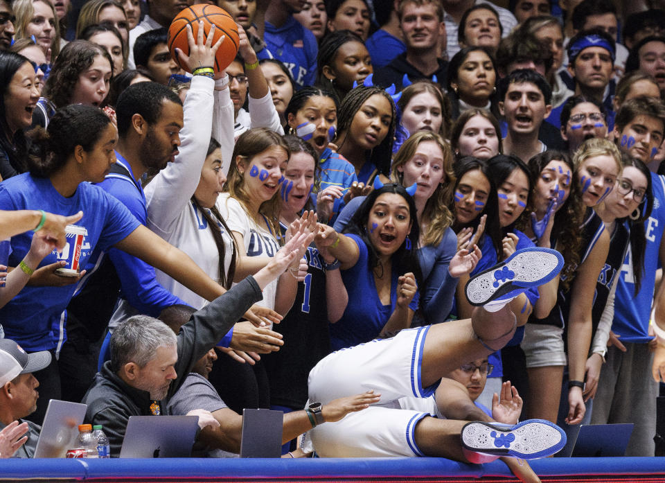 Duke's Sean Stewart, foreground, falls over the media table while trying to save the ball during the second half of an NCAA college basketball game against Clemson in Durham, N.C., Saturday, Jan. 27, 2024. (AP Photo/Ben McKeown)