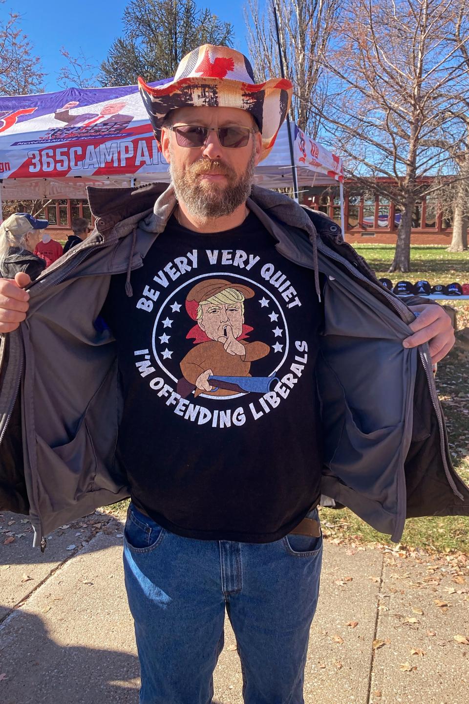 A man in a T-shirt that says, "Be very quiet I'm offending liberals" with a photo of Trump dressed as Elmer Fudd.