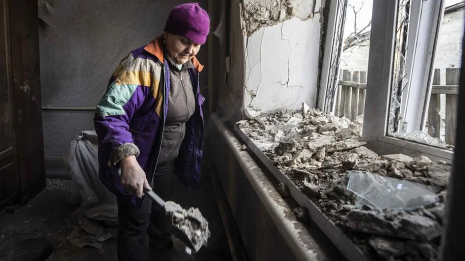Una mujer recoge los escombros tras una explosi&#xf3;n en Donetsk