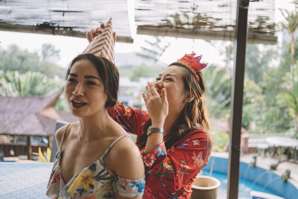 a candid moment where an asian chinese female helping her sister to tie up the party hat getting ready for the birthday celebration event