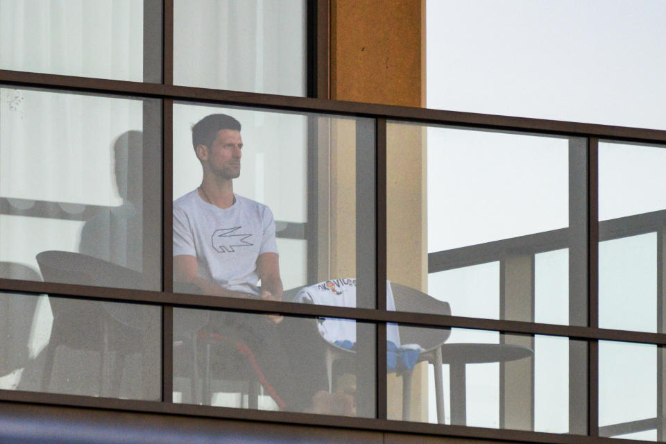 Men's singles world number one tennis player Novak Djokovic of Serbia sits on his hotel balcony in Adelaide on January 18, 2021, one of the locations where players have quarantined for two weeks upon their arrival ahead of the Australian Open tennis tournament in Melbourne.  / Credit: BRENTON EDWARDS / Getty Images