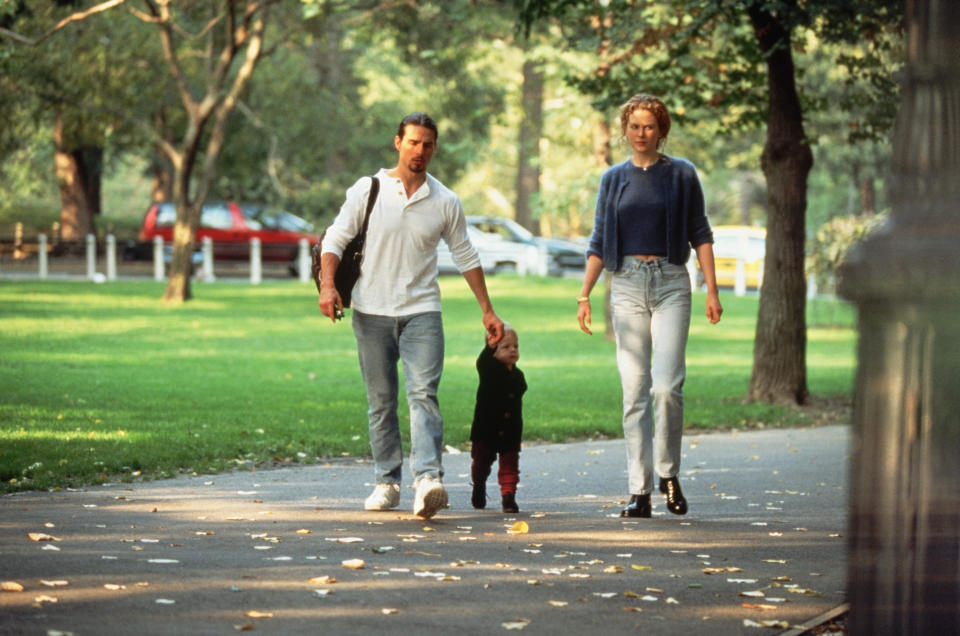 Tom's holding Bella's hand as they walk on a path near grass