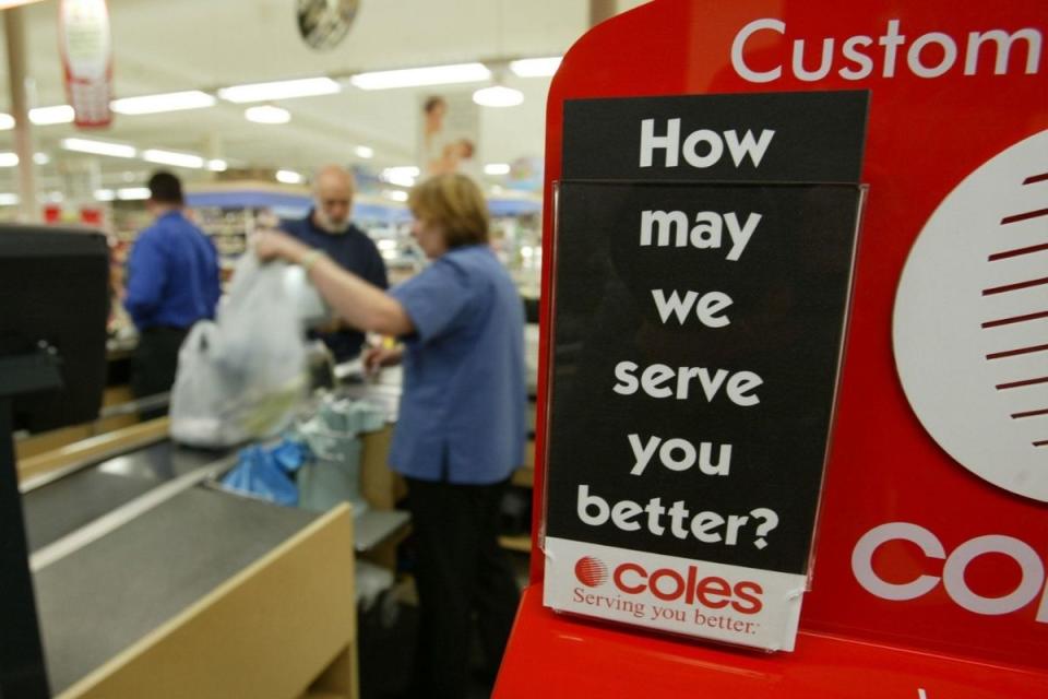 Coles staffer serves customer at checkout. Source: Getty Images