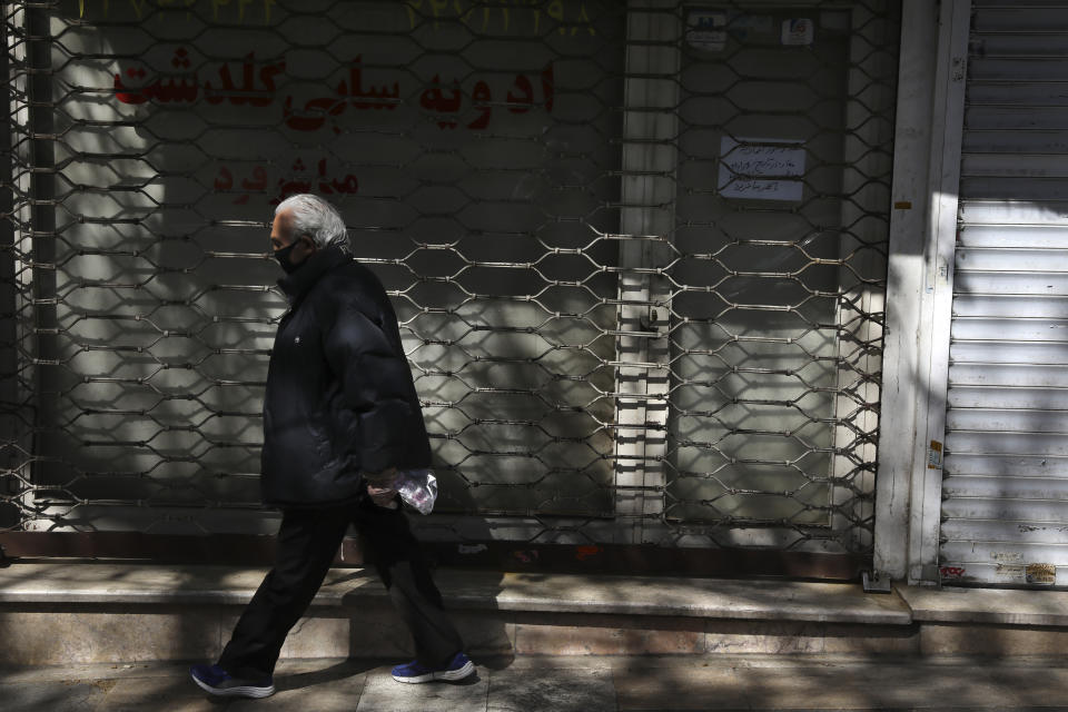 A man wearing a face mask and gloves to protect against the new coronavirus walks past closed shops in northern Tehran, Iran, Saturday, April 4, 2020. In the first working day after Iranian New Year holidays authorities have allowed some government offices and businesses to re-open with limited working hours, when schools, universities, and many businesses still are ordered to be closed aimed to prevent the spread of the virus. (AP Photo/Vahid Salemi)