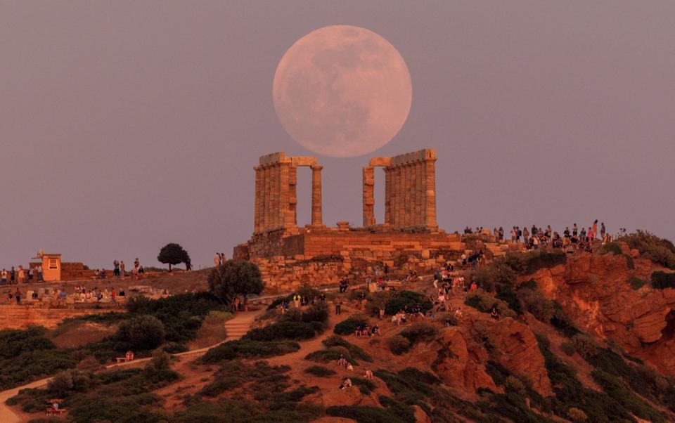 People watch a full moon, known as the "Flower Moon", rising behind the Temple of Poseidon, before a lunar eclipse near Athens, Greece - ALKIS KONSTANTINIDIS/REUTERS