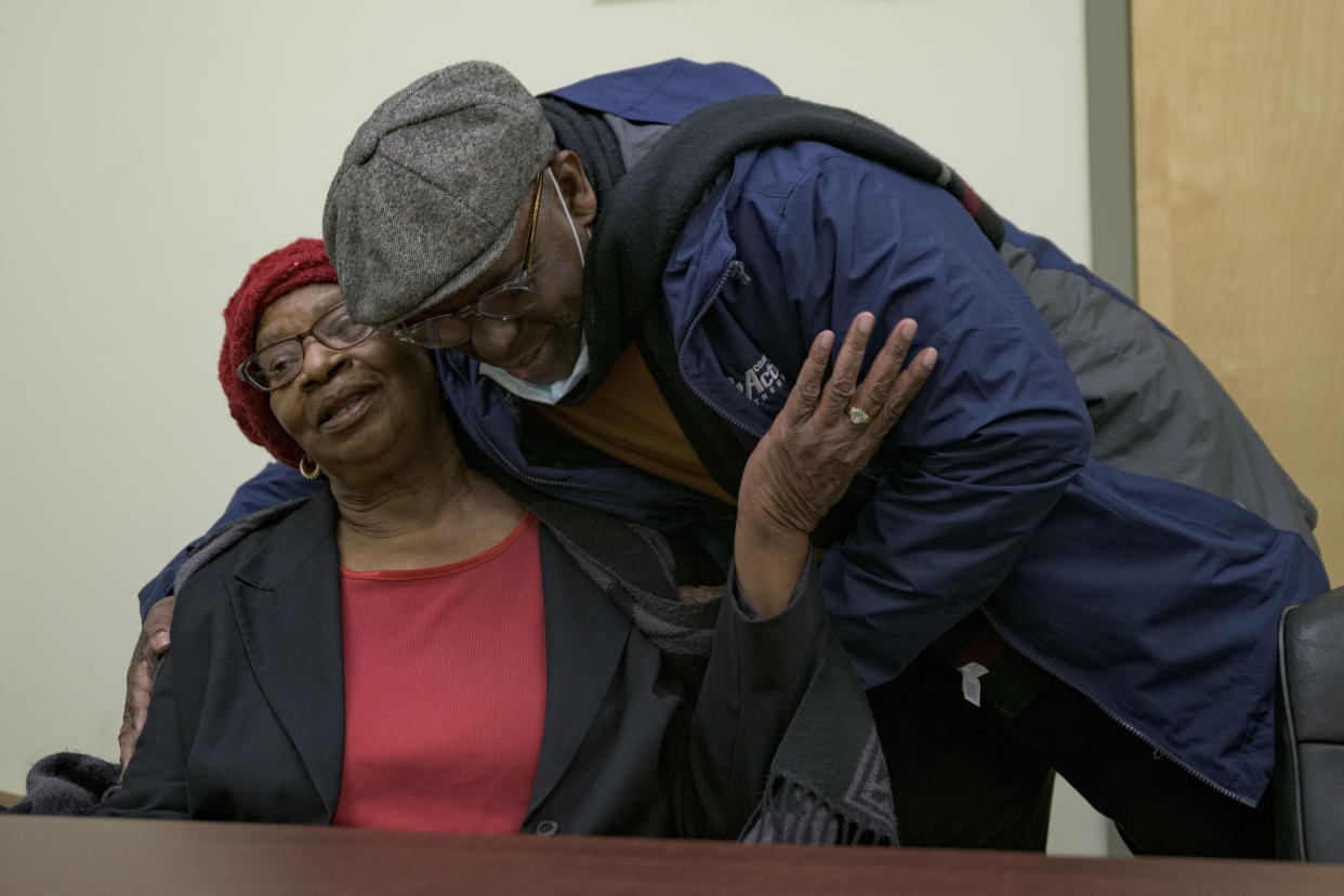 Mary Boyd is hugged by Glenis Scott at Total Community Action in New Orleans, Friday, Feb. 4, 2022. Boyd, who is 83 and lives in New Orleans, said her expensive energy utility bills from Entergy — a major utility provider in Louisiana and three other Southern states — were causing her to choose between medication, and other expenses such as repairing the damage to her fence caused by Hurricane Ida. (AP Photo/Matthew Hinton)