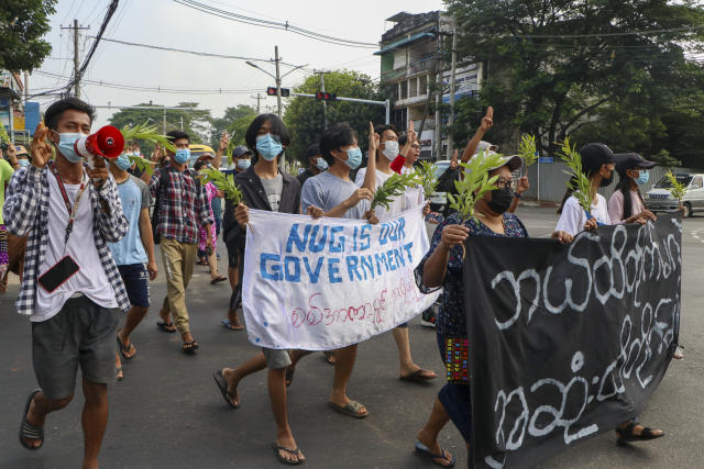 Anti-coup protesters flash the three-finger salute, holding a banner during a demonstration against the military coup in Yangon, Myanmar, Monday, April 26, 2021. Southeast Asian leaders have demanded an immediate end to killings and the release of political detainees in Myanmar during an emergency summit in Jakarta with its top general and coup leader. (AP Photo)