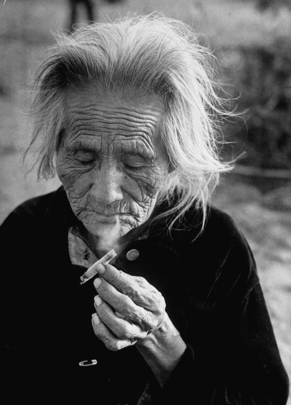 A Navajo woman smoking a hand rolled cigarette.