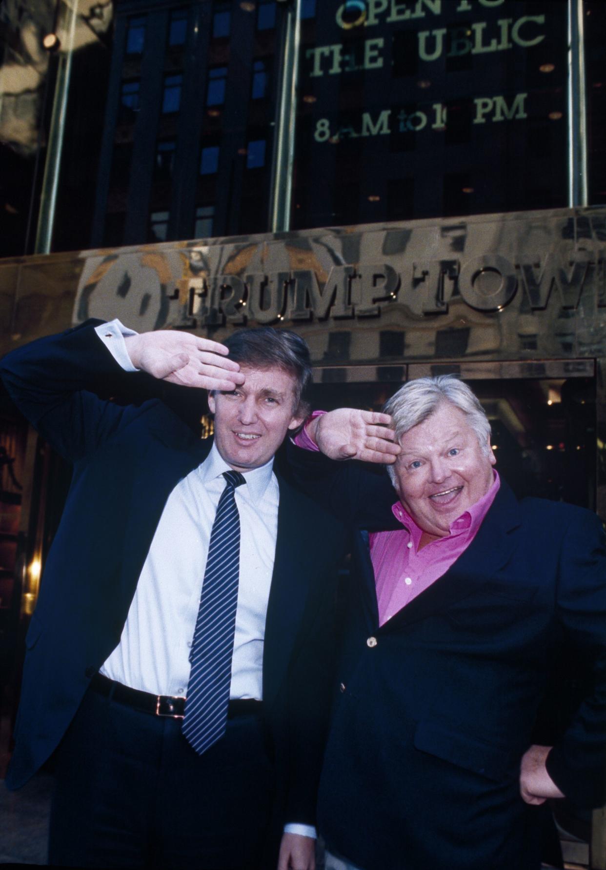 Donald Trump, left, mimics the trademark Benny Hill salute as he and Hill pose for a photo in front of Trump Tower in New York, on Nov. 17, 1989. Hill is in New York scouting locations for an April 1990 television special.