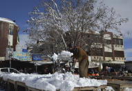 A vendor removes snow from his stall after heavy snowfall in Quetta, capital of Pakistan's southwestern Baluchistan province, Monday, Jan. 13, 2020. Severe winter weather has struck parts of Afghanistan and Pakistan with heavy snowfall, rains and flash floods that left more than 54 dead, officials said Monday as authorities struggled to clear and reopen highways and evacuate people to safer places. (AP Photo/Arshad Butt)