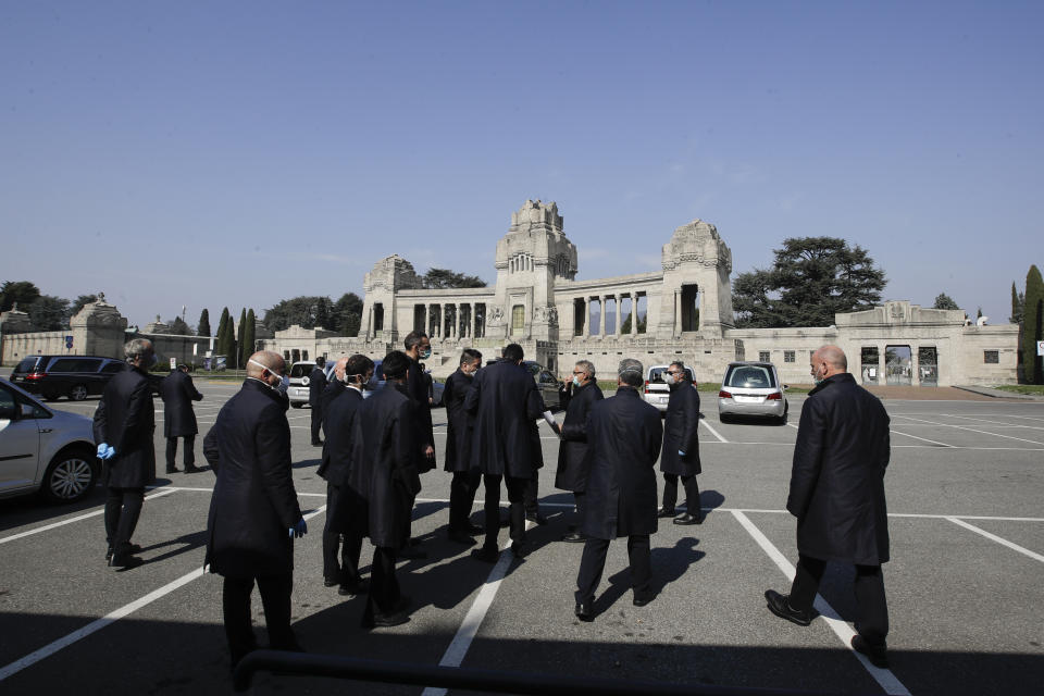 FILE - In this Tuesday, March 17, 2020 file photo, pallbearers stand outside the Monumentale cemetery, in Bergamo, the heart of the hardest-hit province in Italy’s hardest-hit region of Lombardy, Italy. Italy is seeing a slight stabilizing in its confirmed coronavirus infections two weeks into the world’s most extreme nationwide shutdown, but the virus is taking its silent spread south after having ravaged the health care system in the north. The new coronavirus causes mild or moderate symptoms for most people, but for some, especially older adults and people with existing health problems, it can cause more severe illness or death. (AP Photo/Luca Bruno, File)