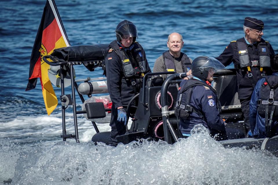 German Chancellor Olaf Scholz on a boat with a German flag and servicemen