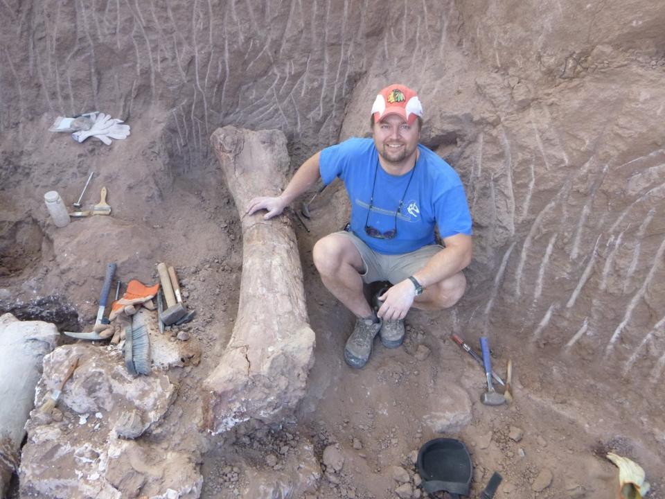 Paleontologist Peter Makovicky shown posing next to the dinosaur's femur still in the grown.