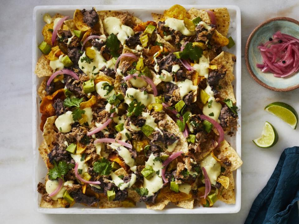 <p>Although these pork and black bean nachos require a bit more attention than your <a href="https://www.myrecipes.com/recipe/quick-easy-nachos" rel="nofollow noopener" target="_blank" data-ylk="slk:basic platter of loaded nachos;elm:context_link;itc:0;sec:content-canvas" class="link ">basic platter of loaded nachos</a>, they’re well worth the effort. These are the nachos to make when you really wanna go next-level and impress a group. With the succulent pork, Swiss cheese and mustard sauce, and bread-and-butter pickles, this crowd-pleasing play on a Cuban sandwich packs a powerful load of flavor. Although they may seem out of place at first glance, the briny-sweet pickles are a perfect balance for the savory pork and the funky Swiss cheese sauce. As for the homemade refried black beans, you’ll never look back once you try them. Going for refried beans is one of our favorite pro-tricks when it comes to building a superior plate of nachos; they’re creamy, flavorful, and actually stay on the chip! We’ve linked to <a href="https://editor.myrecipes.com/recipe/pork-shoulder-roast-citrus-mojo-green-sauce" rel="nofollow noopener" target="_blank" data-ylk="slk:a pork recipe;elm:context_link;itc:0;sec:content-canvas" class="link ">a pork recipe</a> in the ingredient list below that would be excellent for these nachos (let’s be real, it would be excellent for just about anything), however, this roasted pork shoulder is time intensive to prepare—so if you’re not up for that, you can definitely use cooked, shredded pork (without sauce) from your favorite local BBQ joint or supermarket instead. </p> <p><a href="https://www.myrecipes.com/recipe/cuban-nachos" rel="nofollow noopener" target="_blank" data-ylk="slk:Cuban Nachos Recipe;elm:context_link;itc:0;sec:content-canvas" class="link ">Cuban Nachos Recipe</a></p>