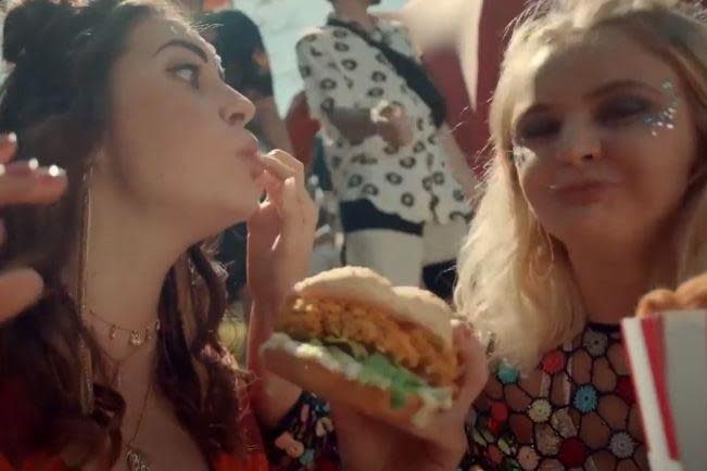 The ad ends with the woman tucking into a Zinger meal with her friends (KFC)