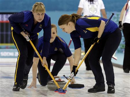 Sweden's Christina Bertrup (C) delivers a stone as teammates vice Maria Prytz (L) and Maria Wennerstroem sweep the ice during their women's curling semifinal game against Switzerland at the 2014 Sochi Winter Olympics in the Ice Cube Curling Center in Sochi February 19, 2014. REUTERS/Ints Kalnins