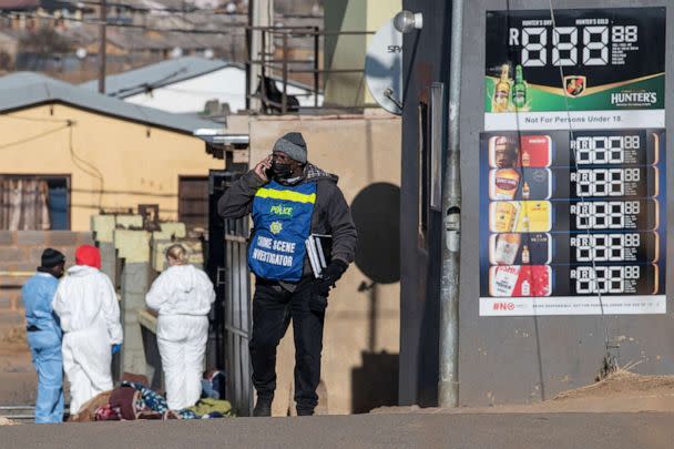 PHOTO: A South African Police Service crime scene investigator talks on his phone at the scene of a mass shooting in Soweto, South Africa, on July 10, 2022. (Ihsaan Haffejee/AFP via Getty Images)