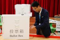 A polling official opens a ballot box to count the votes of the Hong Kong council elections, in a polling station in Hong Kong