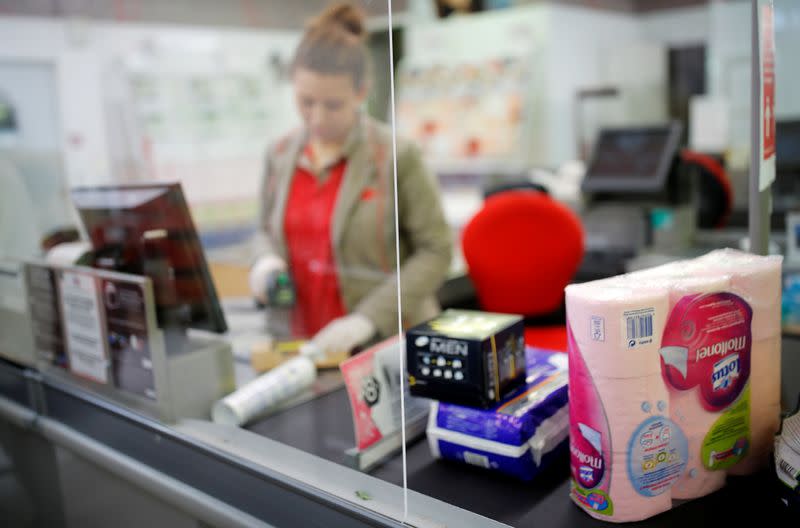 A cashier serves a customer behind a plastic protection shield at a supermarket in Coueron near Nantes