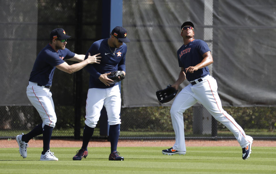 Houston Astros outfielders Josh Reddick and George Springer duck for cover as Michael Brantley runs after a fly ball during spring training baseball practice, Tuesday, Feb. 18, 2020 in West Palm Beach, Fla. (Karen Warren/Houston Chronicle via AP)