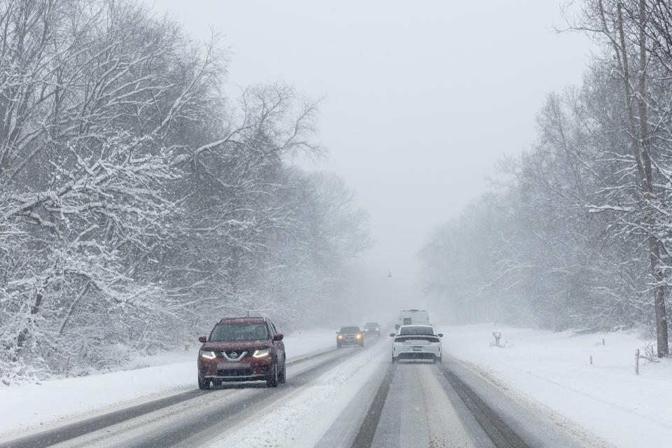 Vehicles drive along a snow covered Wilson Road in Grandville, Mich., on Friday, Nov. 18, 2022. (Joel Bissell/The Grand Rapids Press via AP)