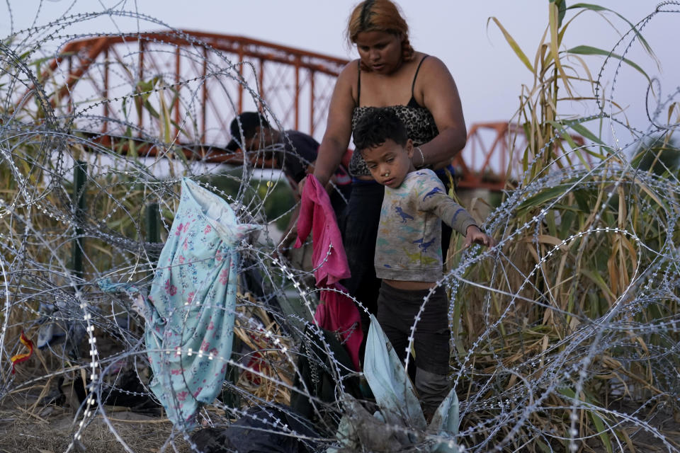 Migrants climb over concertina wire after they crossed the Rio Grande and entered the U.S. from Mexico, Saturday, Sept. 23, 2023, in Eagle Pass, Texas. (AP Photo/Eric Gay)