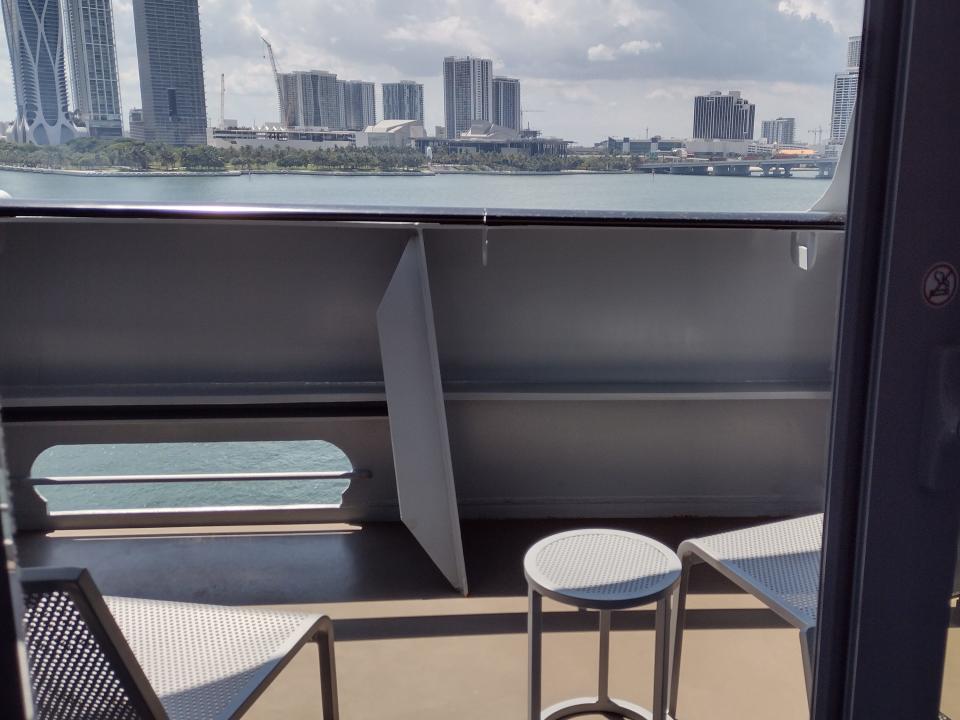 A balcony on a cruise ship with two chairs and a small table.