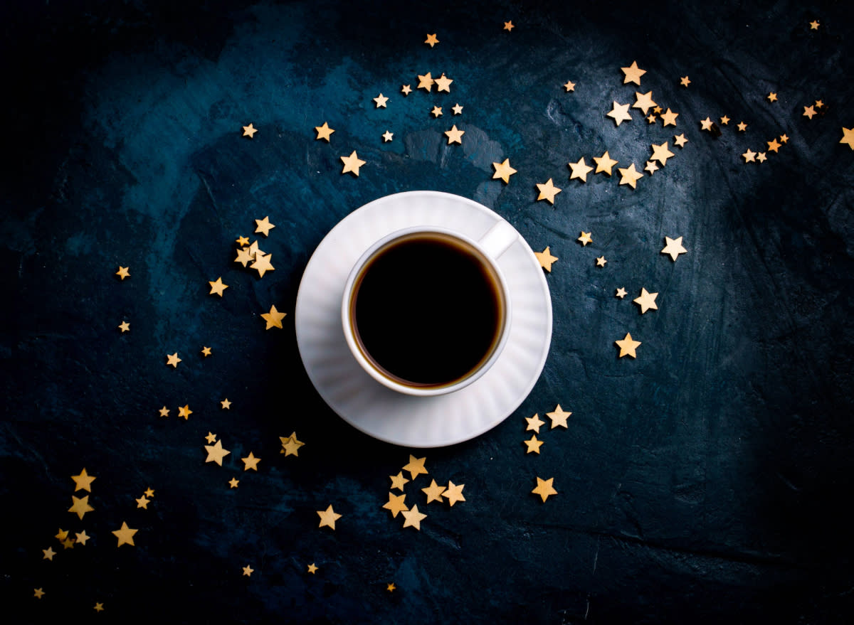 coffee on saucer on black table surrounded by gold stars