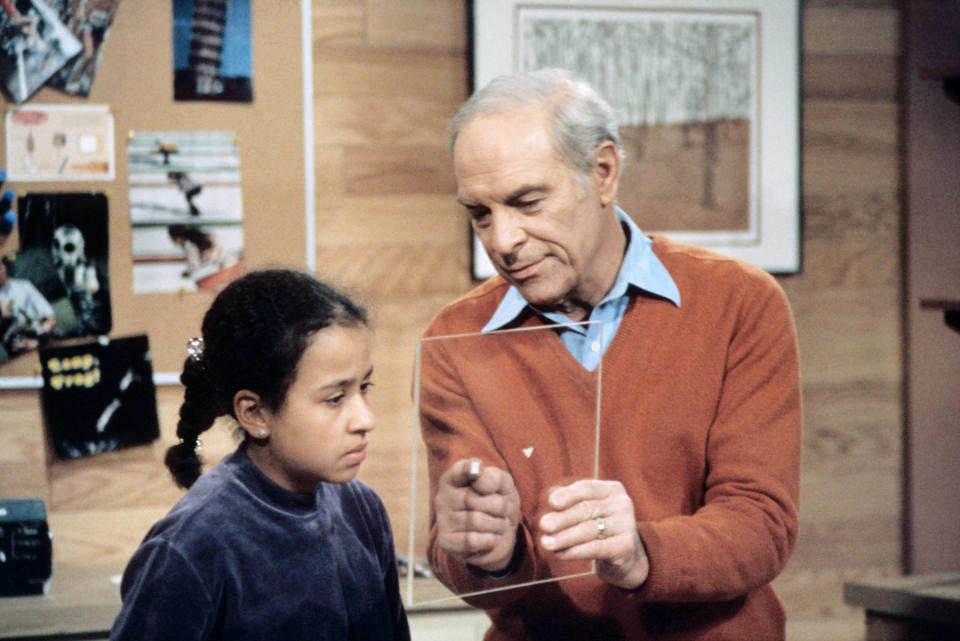 Mr. Wizard holding piece of glass and point at a square on it with a little girl looking too