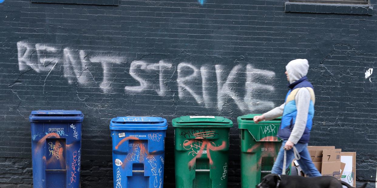 A pedestrian walks past graffiti that reads "Rent Strike" Wednesday, April 1, 2020, in Seattle, Washington.(AP Photo:Ted S. Warren)