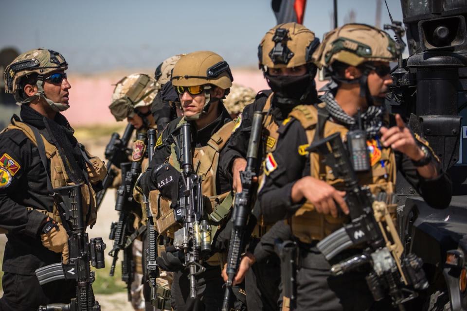 Italian soldiers, deployed in support of Operation Inherent Resolve, and members of the Iraqi counter-terrorism force use a military fighting vehicle as cover before moving towards an objective during military training in Mosul, Iraq, April 5, 2018.