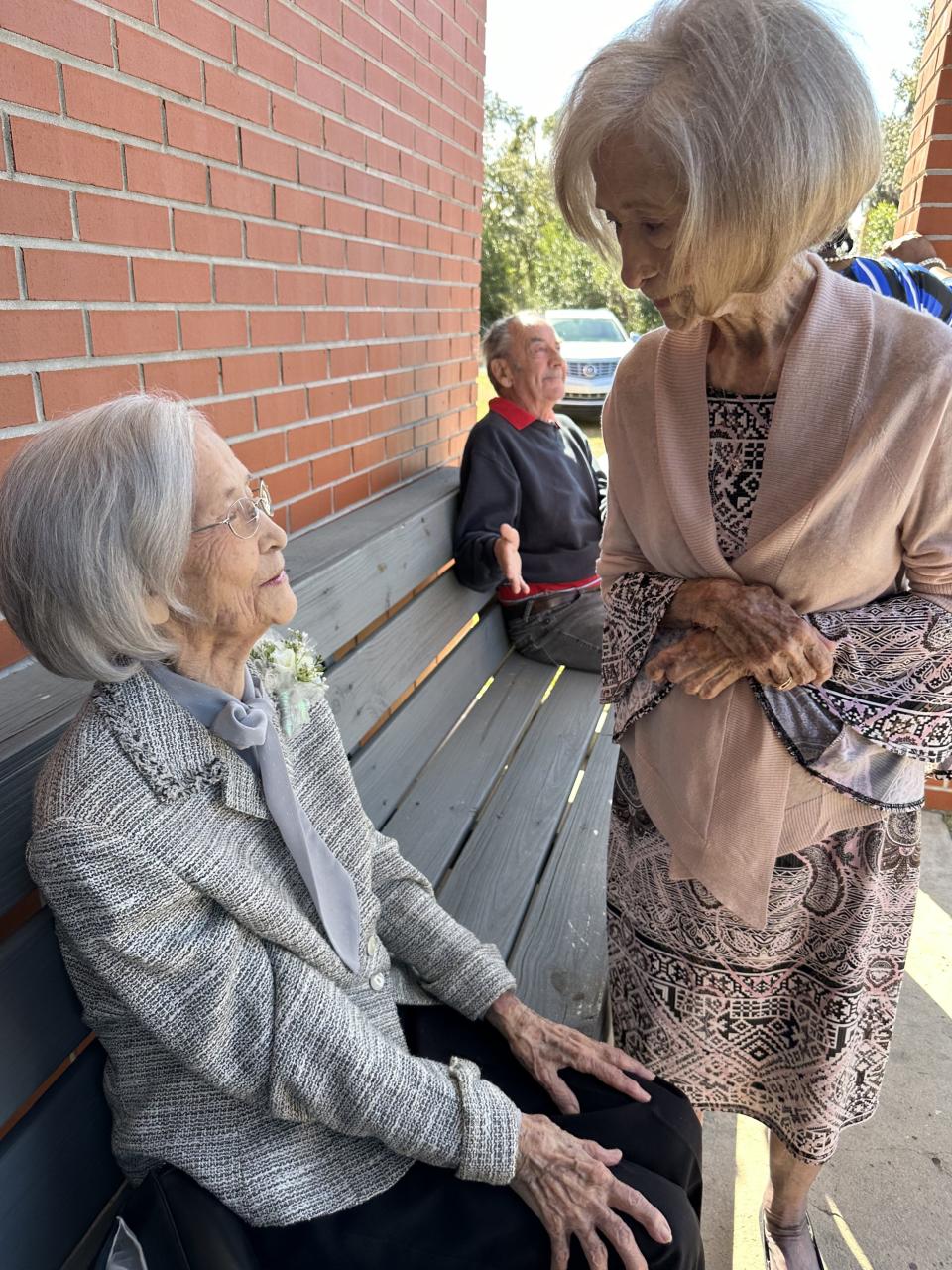 Era Luckie Daniell, seated, chats with her twin sister Vera Rozier prior to going inside for their 100th birthday party.