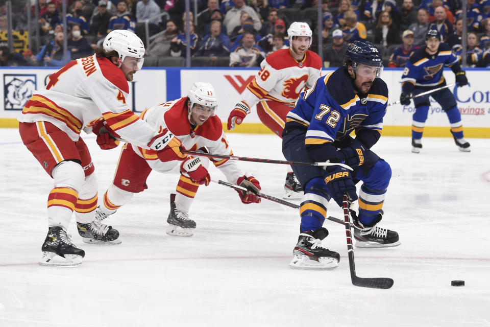 Calgary Flames defenseman Rasmus Andersson (4) and left wing Johnny Gaudreau (13) defend against St. Louis Blues defenseman Justin Faulk (72) during the second period of an NHL hockey game Thursday, Jan. 27, 2022, in St. Louis. (AP Photo/Joe Puetz)