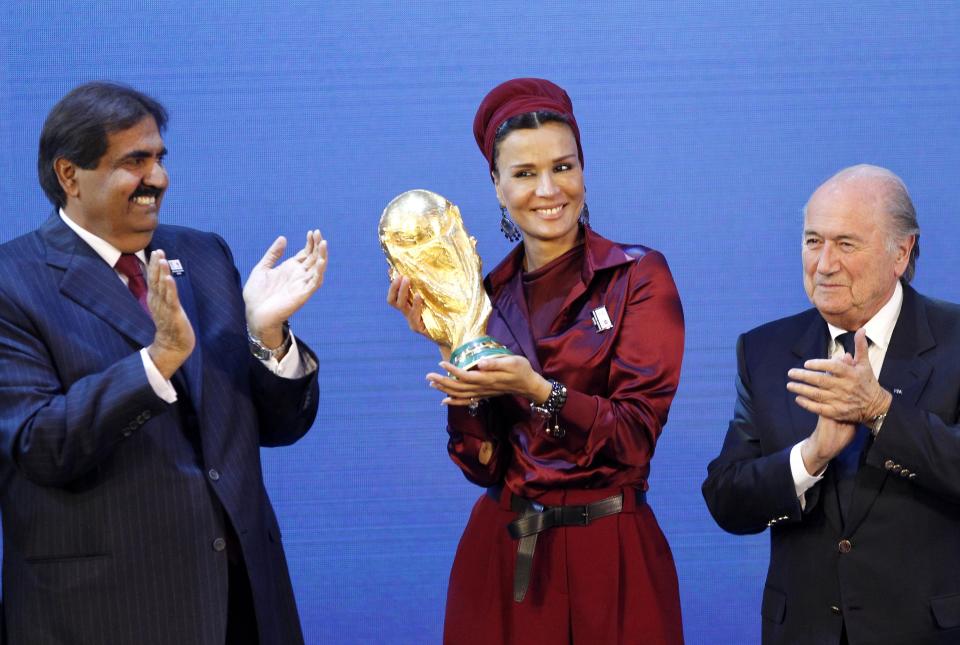 FILE - Sheikh Hamad bin Khalifa Al-Thani, Emir of Qatar, left, and FIFA President Joseph Blatter, right, applaud, as Sheika Mozah bint Nasser al-Misned holds the World Cup trophy, after the announcement of Qatar hosting the 2022 soccer World Cup in Zurich, Switzerland, Thursday, Dec. 2, 2010. Hosting the World Cup marks a pinnacle in Qatar's efforts to rise out of the shadow of its larger neighbors in the wider Middle East. (AP Photo/Michael Probst, File)