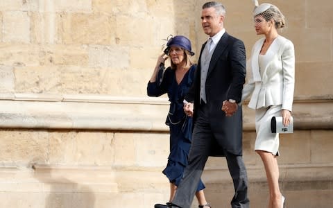 Robbie Williams arrives as his mother's hat is blown from her head - Credit: AFP