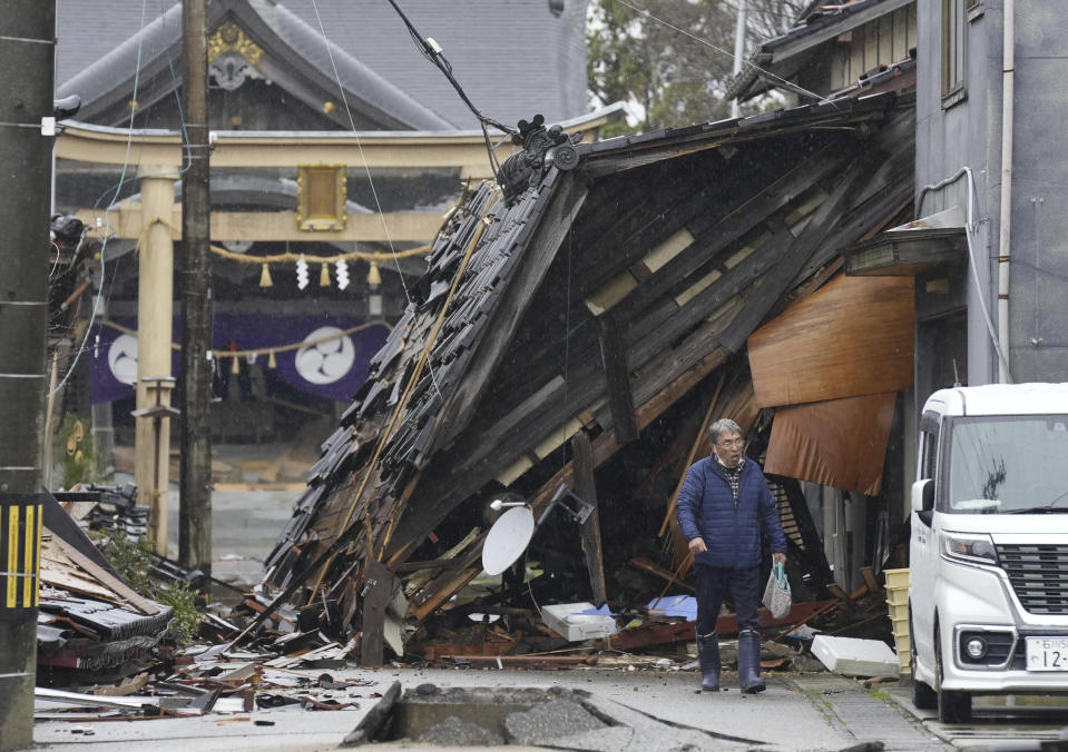 A man walks in front of a destroyed house in Suzu, Ishikawa prefecture, Japan Sunday, Jan. 7, 2024. A major earthquake slammed western Japan on Jan. 1, killing scores of people, toppling buildings and setting off landslides. (Kyodo News via AP)