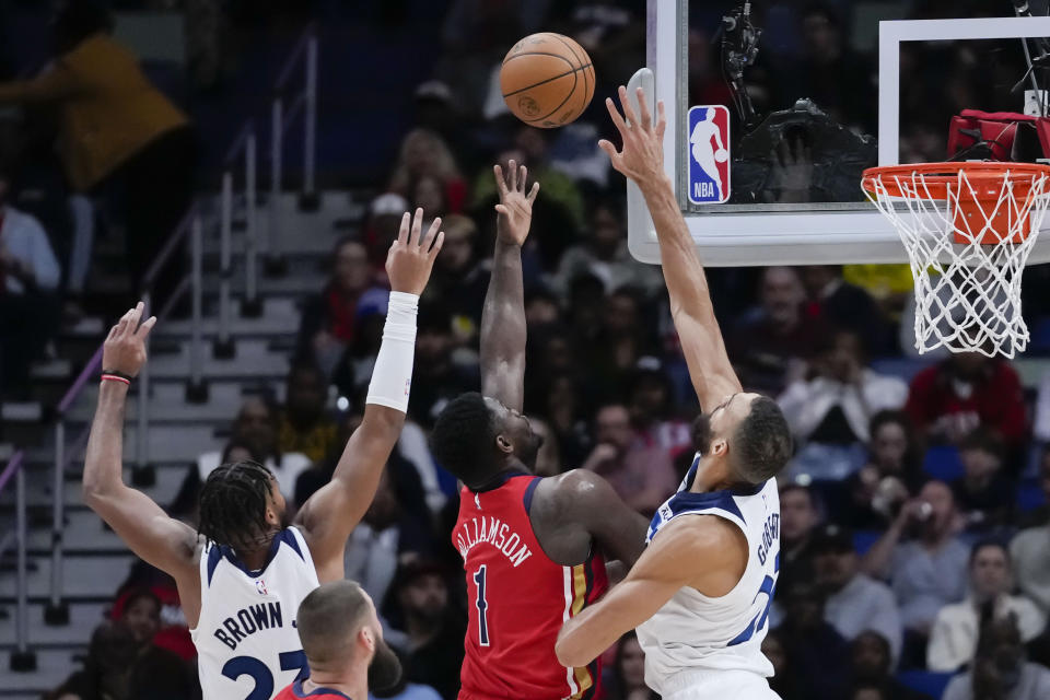 New Orleans Pelicans forward Zion Williamson (1) shoots between Minnesota Timberwolves forward Troy Brown Jr. and center Rudy Gobert in the second half of an NBA basketball game in New Orleans, Monday, Dec. 11, 2023. The Pelicans won 121-107. (AP Photo/Gerald Herbert)