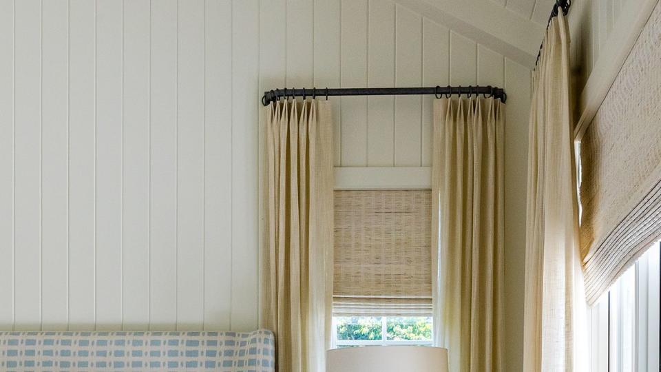 a bedroom with blue and white bed frame and window with shade and curtains