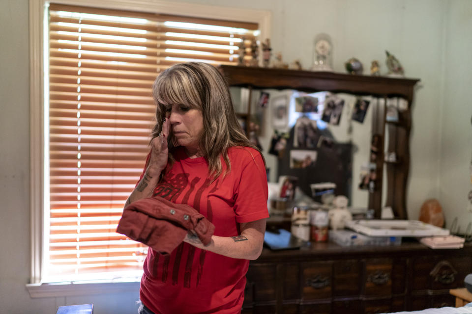 Barbie Rohde wipes away a tear Friday, June 9, 2023, at her home in Flint, Texas, as she holds the T-shirt of her son, Army Sgt. Cody Bowman, who took his own life. She had been worried about her son. Most of his left hand had been blown off in a training accident. He told his mom he didn’t know if he could continue his military career, and all he’d ever wanted to be was a soldier. He asked for his guns, which she had been holding. She’d hesitated. But they were his, and this is Texas. (AP Photo/David Goldman)