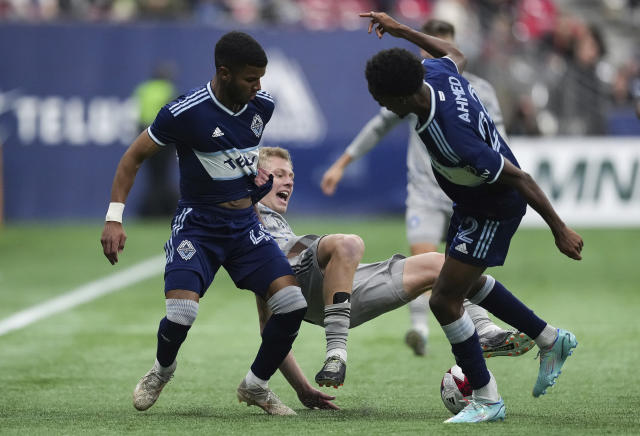 CF Montreal's Robert Thorkelsson, center, falls as he vies for the ball against Vancouver Whitecaps' Pedro Vite, left, and Ali Ahmed during the second half of an MLS soccer match Saturday, April 1, 2023, in Vancouver, British Columbia. (Darryl Dyck/The Canadian Press via AP)