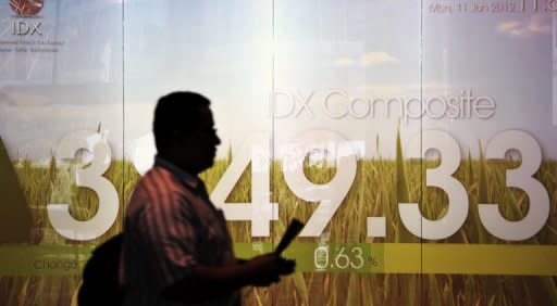 An Indonesian man walks past Jakarta's stock exchange in June 2012. Asian markets fell Friday as apparently coordinated action by Europe and China to stimulate growth failed to reassure wary investors ahead of US jobs data due later in the day