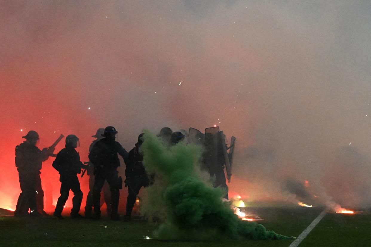 Riot police officers clash with Saint-Etienne's fans who invaded the pitch after being defeated by Auxerre at the end of the French L1-L2 play-off second leg football match between AS Saint-Etienne and AJ Auxerre at the Geoffroy Guichard Stadium in Saint-Etienne, central-eastern France on May 29, 2022. (Photo by JEAN-PHILIPPE KSIAZEK / AFP) (Photo by JEAN-PHILIPPE KSIAZEK/AFP via Getty Images)