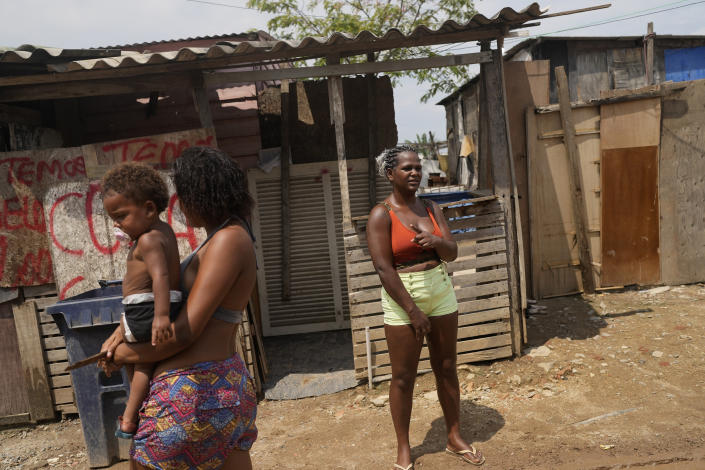 Francielle de Santana, right, stands outside her home in the Jardim Gramacho favela of Rio de Janeiro, Brazil, Monday, Oct. 4, 2021. Due to the rise in gas prices, Santana says she’ll have to go around scraping for any recyclable material to sell to be able to afford to buy a new gas cylinder to cook. (AP Photo/Silvia Izquierdo)