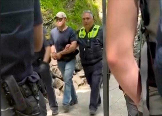 An image taken from video shows a suspect being led away by police officers near Neuschwanstein Castle in  Schwangau, southern Germany, June 15, 2023, after two tourists were attacked near the castle. / Credit: Eric Abneri via AP