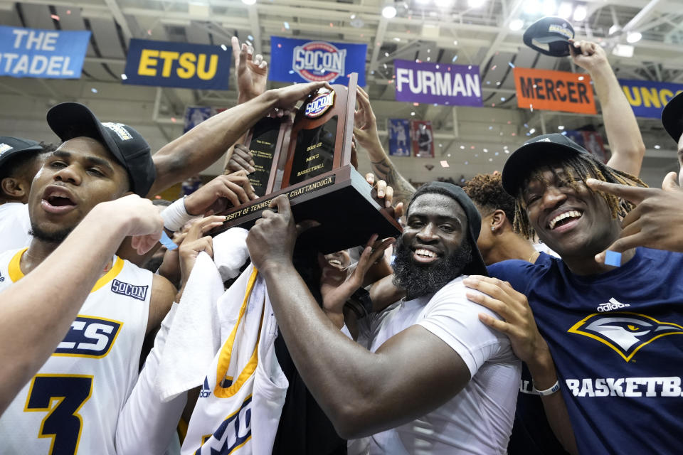 Chattanooga guard David Jean-Baptiste, second from right, holds the championship trophy with teammates to celebrate their win over Furman in an NCAA college basketball championship game for the Southern Conference tournament, Monday, March 7, 2022, in Asheville, N.C. (AP Photo/Kathy Kmonicek)